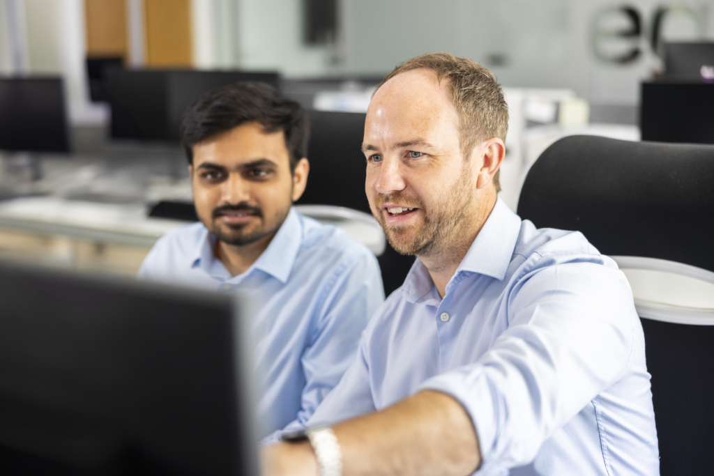 Two male Egniol employees working together on a computer